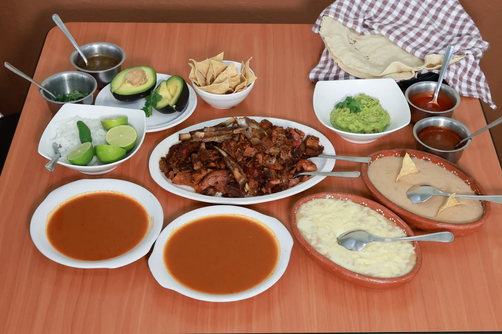 Mesa con birria, consomé, guacamole, frijoles y tortillas de La Tapatía